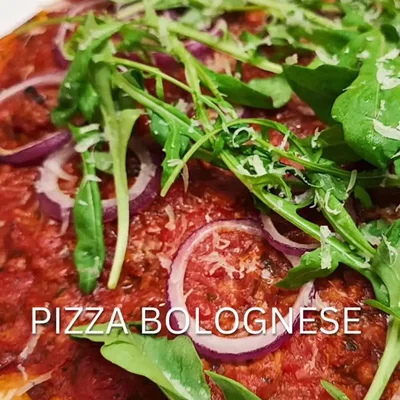Selbstgemachte Pizza mit Bolognese und Rucola