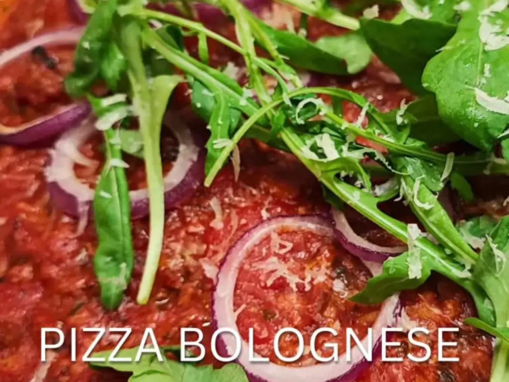 Selbstgemachte Pizza mit Bolognese und Rucola
